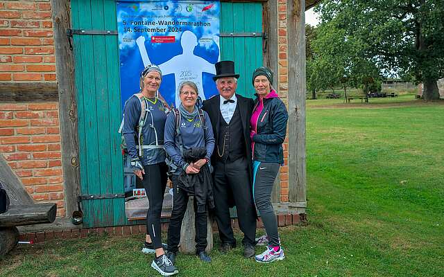 <p>Drei sportlich gekleidete Frauen lassen sich vor einer Fotowand mit Theodor Fontane fotografieren.</p>